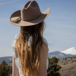 Person wearing a cowboy hat with a mountainous landscape in the background