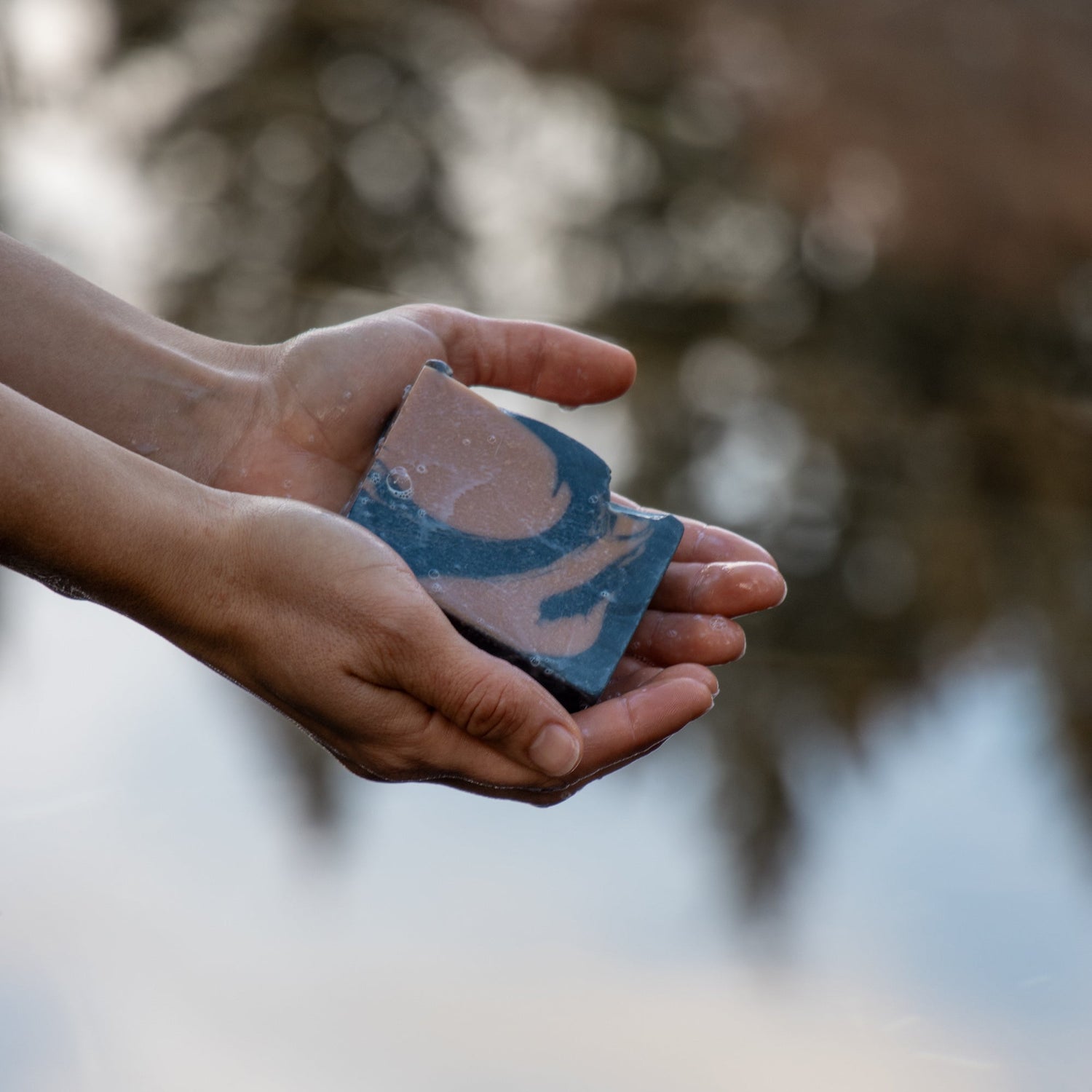 hand holding bar of anaconda copper soap, colored with black and gold colors.